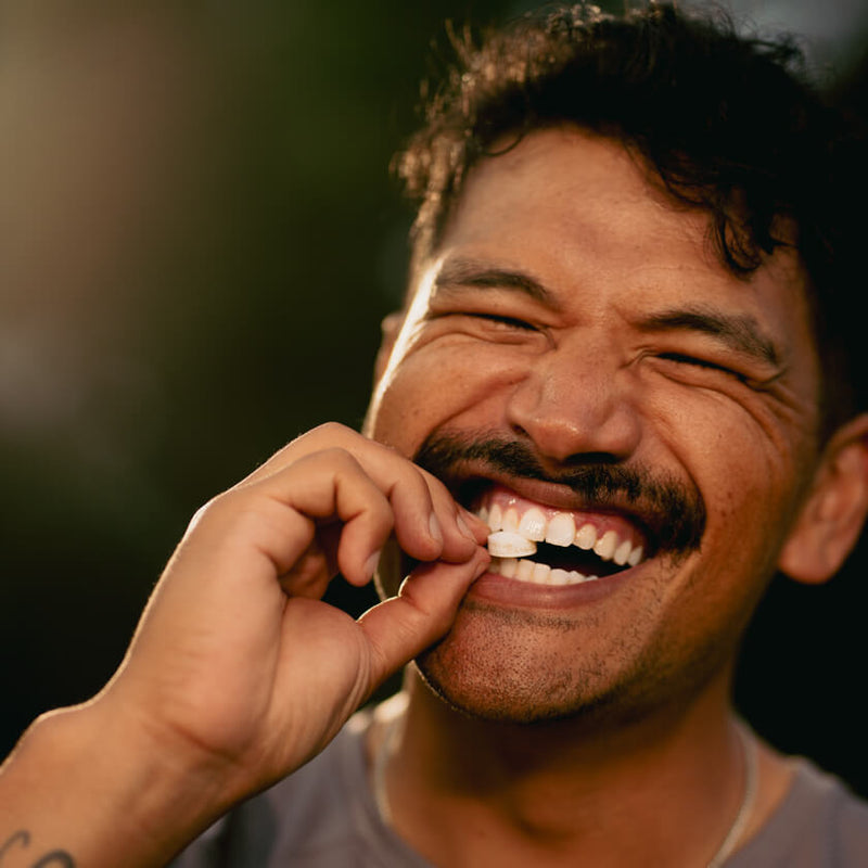 Man smiling while placing a Neuro Energy Gum piece in his mouth
