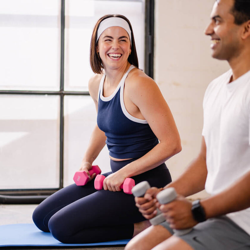 Woman and man working out together with dumbbells indoors