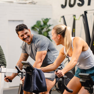 Two people laughing during a spin class at the gym