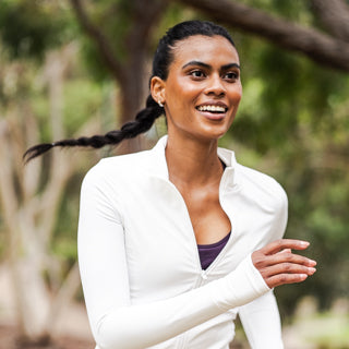 Woman in a white sports jacket smiling outdoors